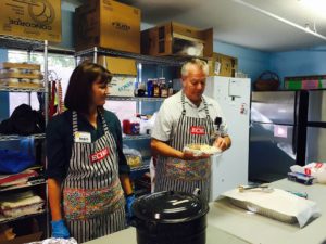 Volunteers prepare food and serve the homeless